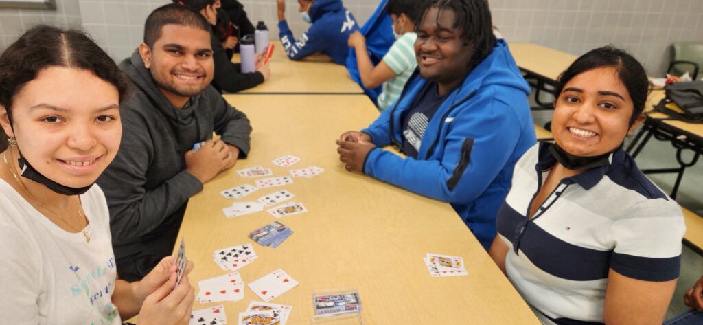 Two male and two female students playing cards in the school cafeteria