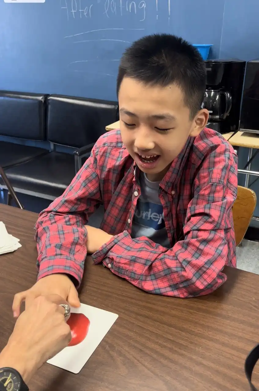 boy wearing striped red and shirt touching a picture of an apple