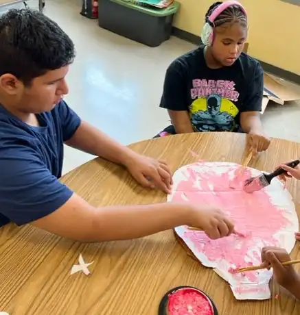 boy and girl using pink pain to color a model of the brain.