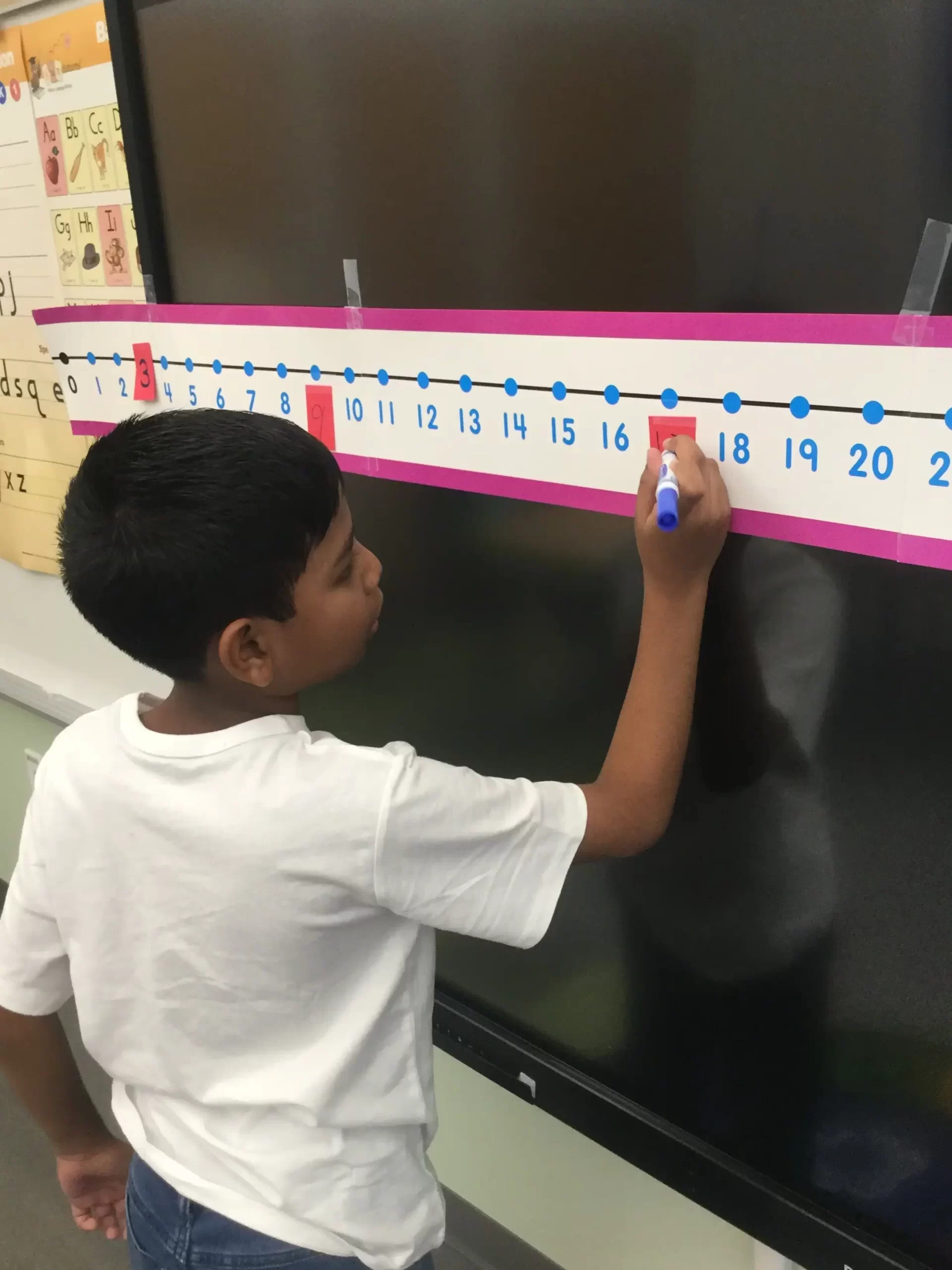 boy wearing a white shirt using a number line to solve number problems.