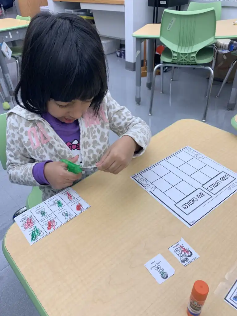 girl cutting picture cards to sort them by category.