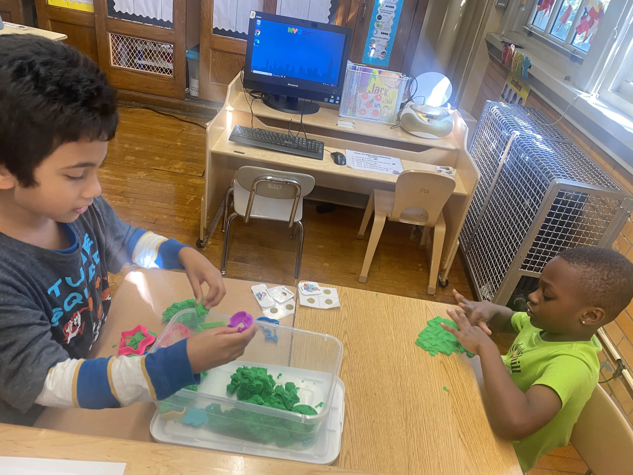 One boy with a blue shirt and a boy with a green shirt using play dough to learn shapes.