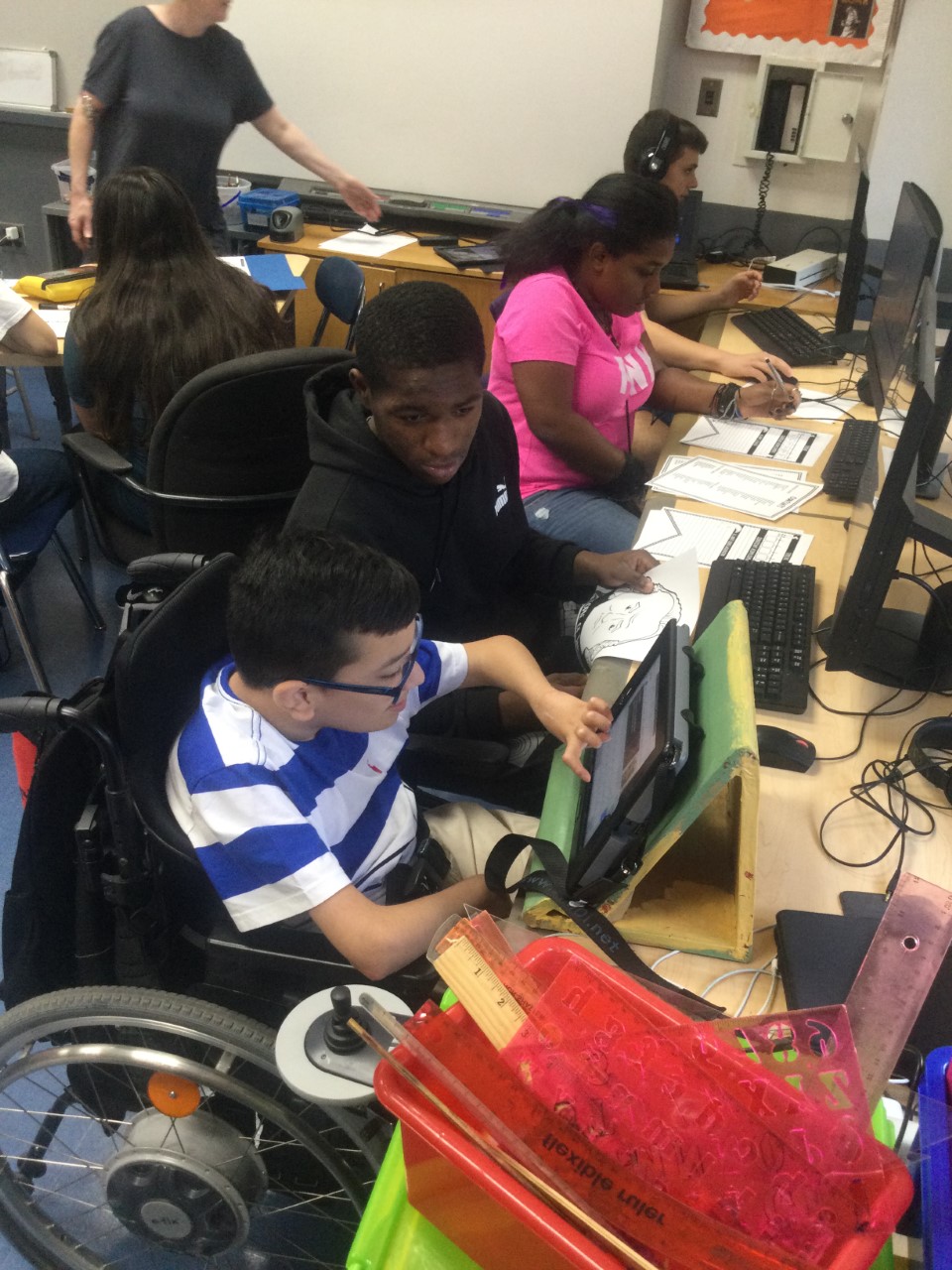 Student in a wheel chair and 3 student in chairs working on computers