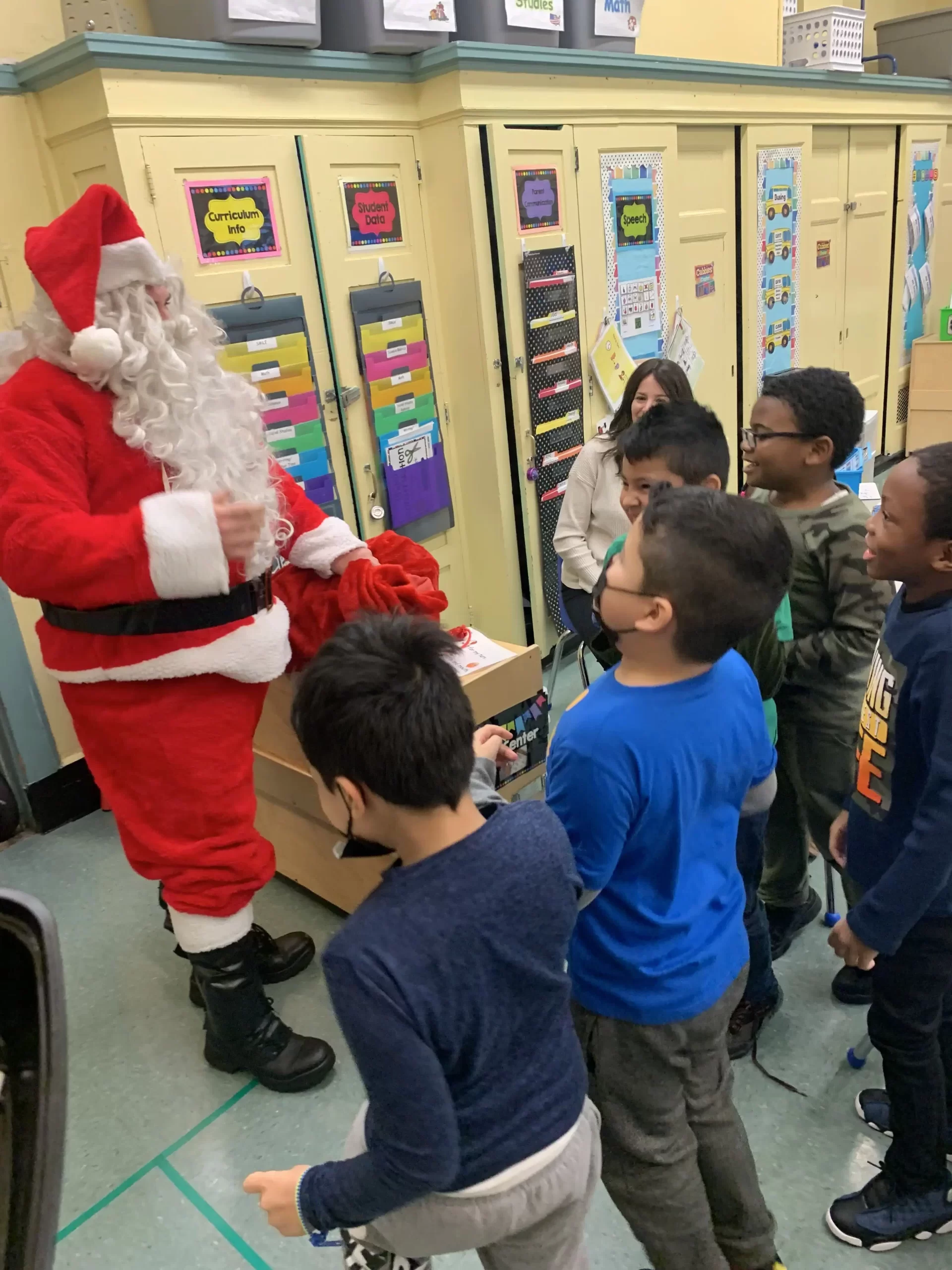 Five elementary school students meeting Santa Clause in their classroom.