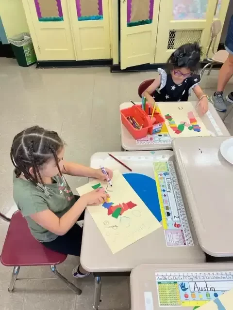 Two students sitting at their desk coloring