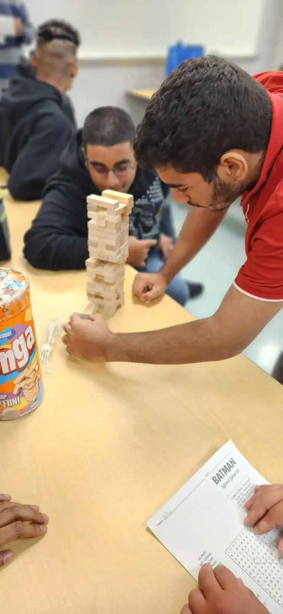 Two male students playing a black game called Jenga in the cafeteria