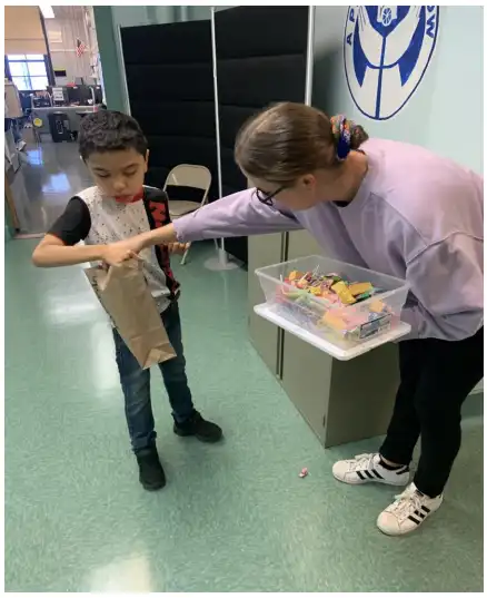 Student holding a bag to collect candy from his teacher