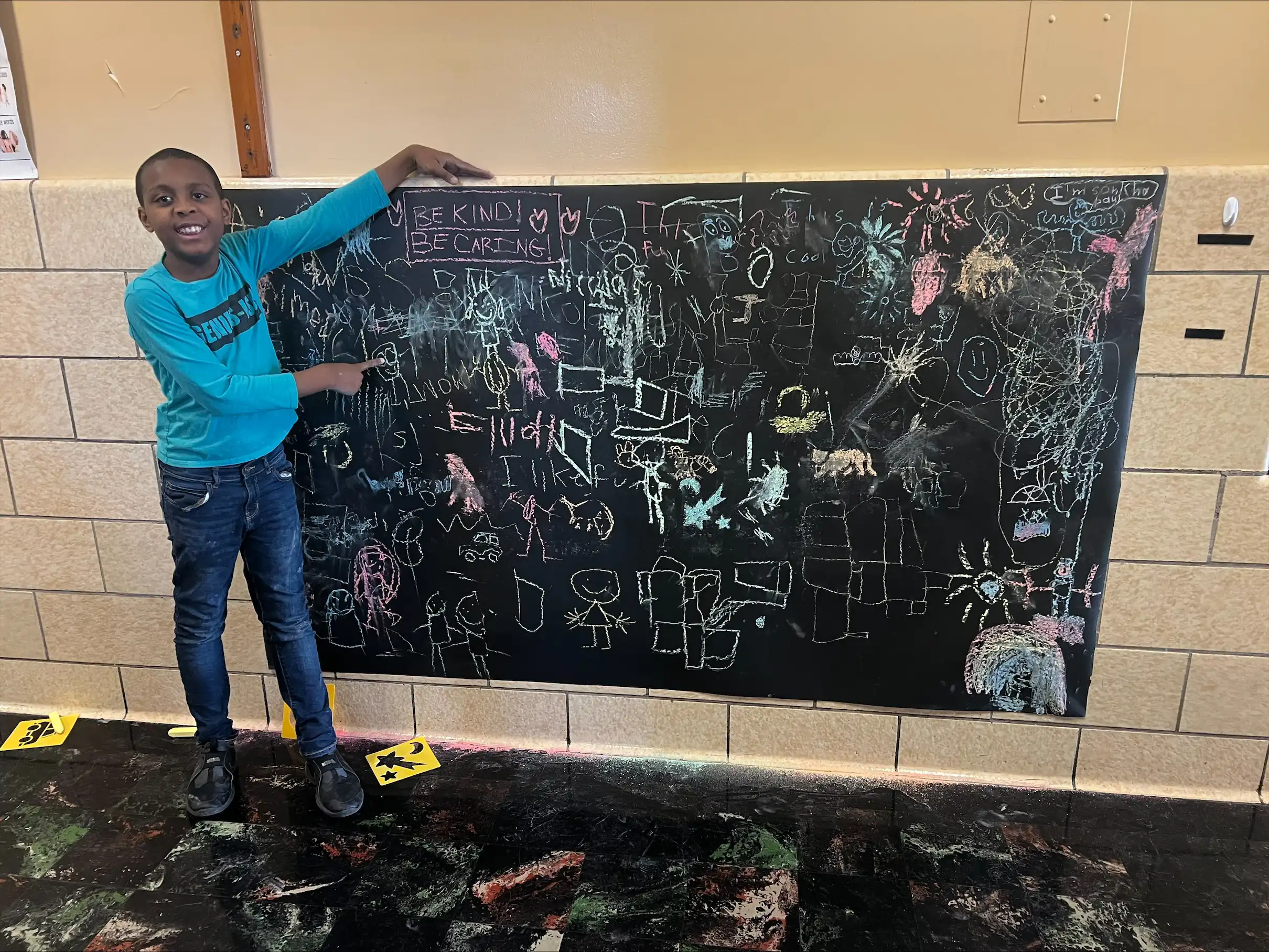 Student drawing positive messages on a chalk board