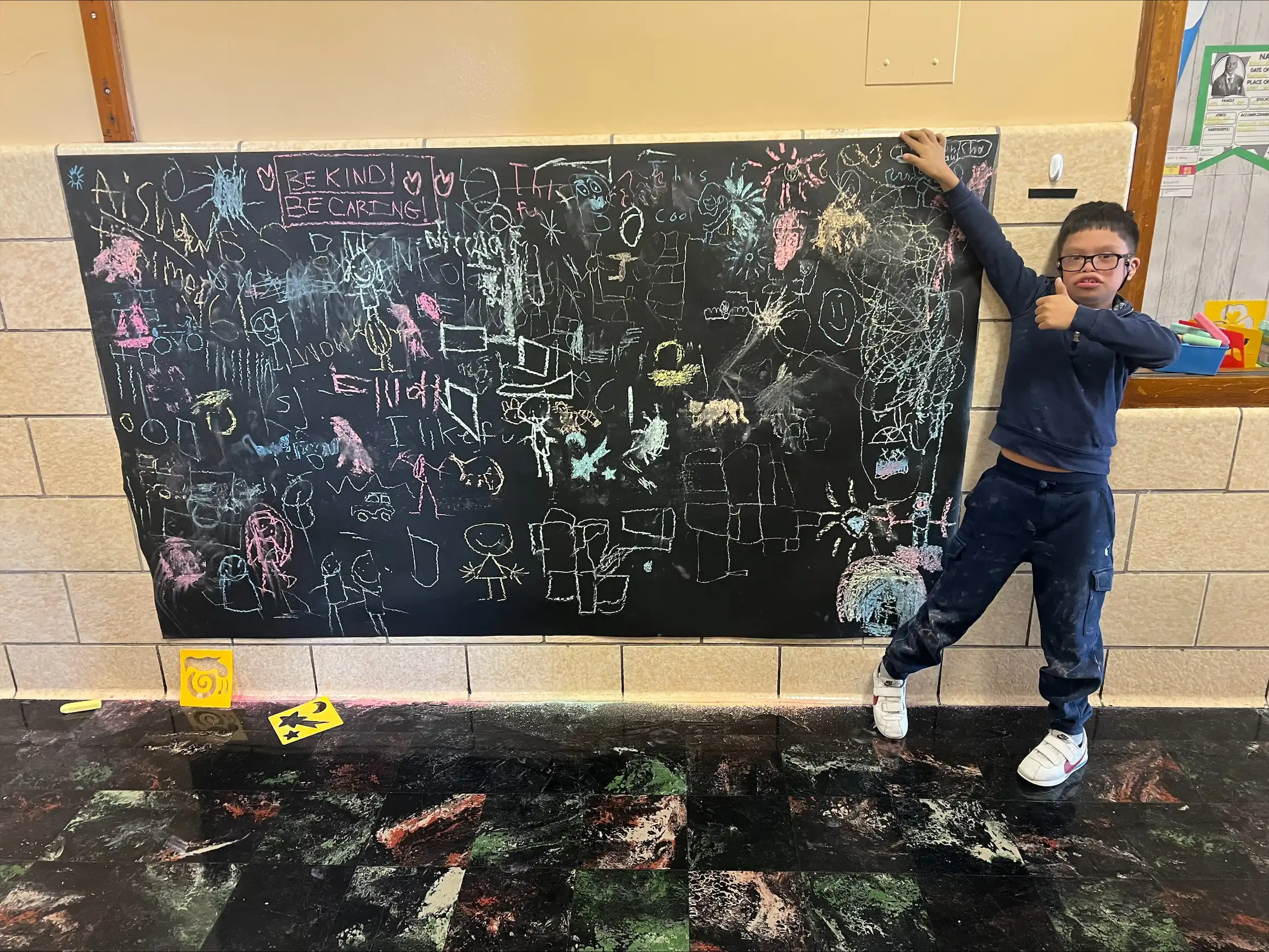 Student drawing positive messages on a chalk board