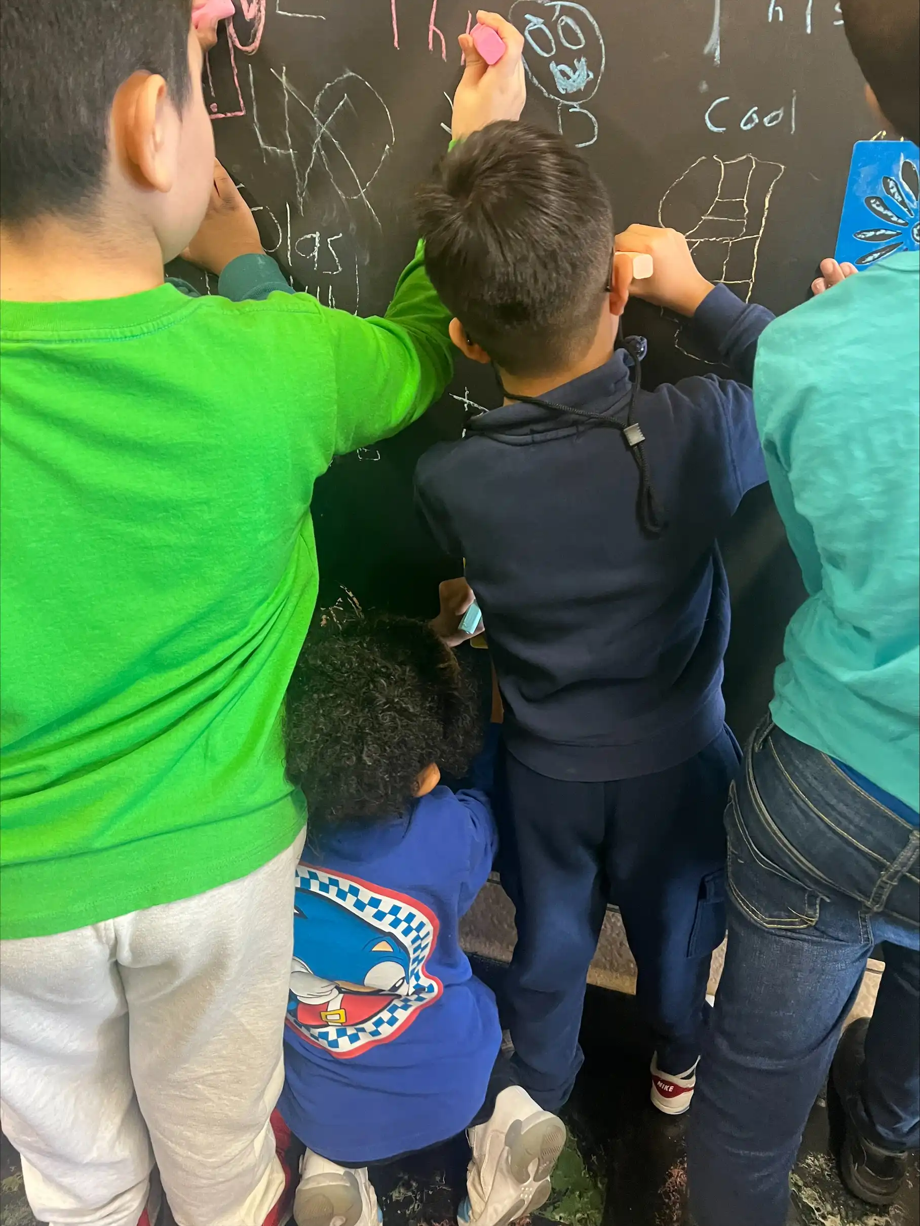 Four students drawing positive messages on a chalk board