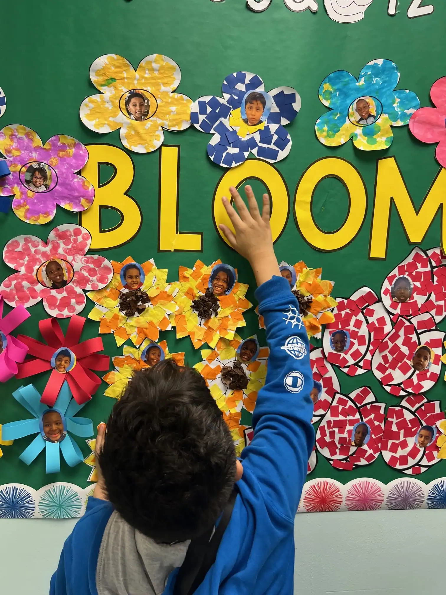 Student putting up the word bloom on a green bulletin board