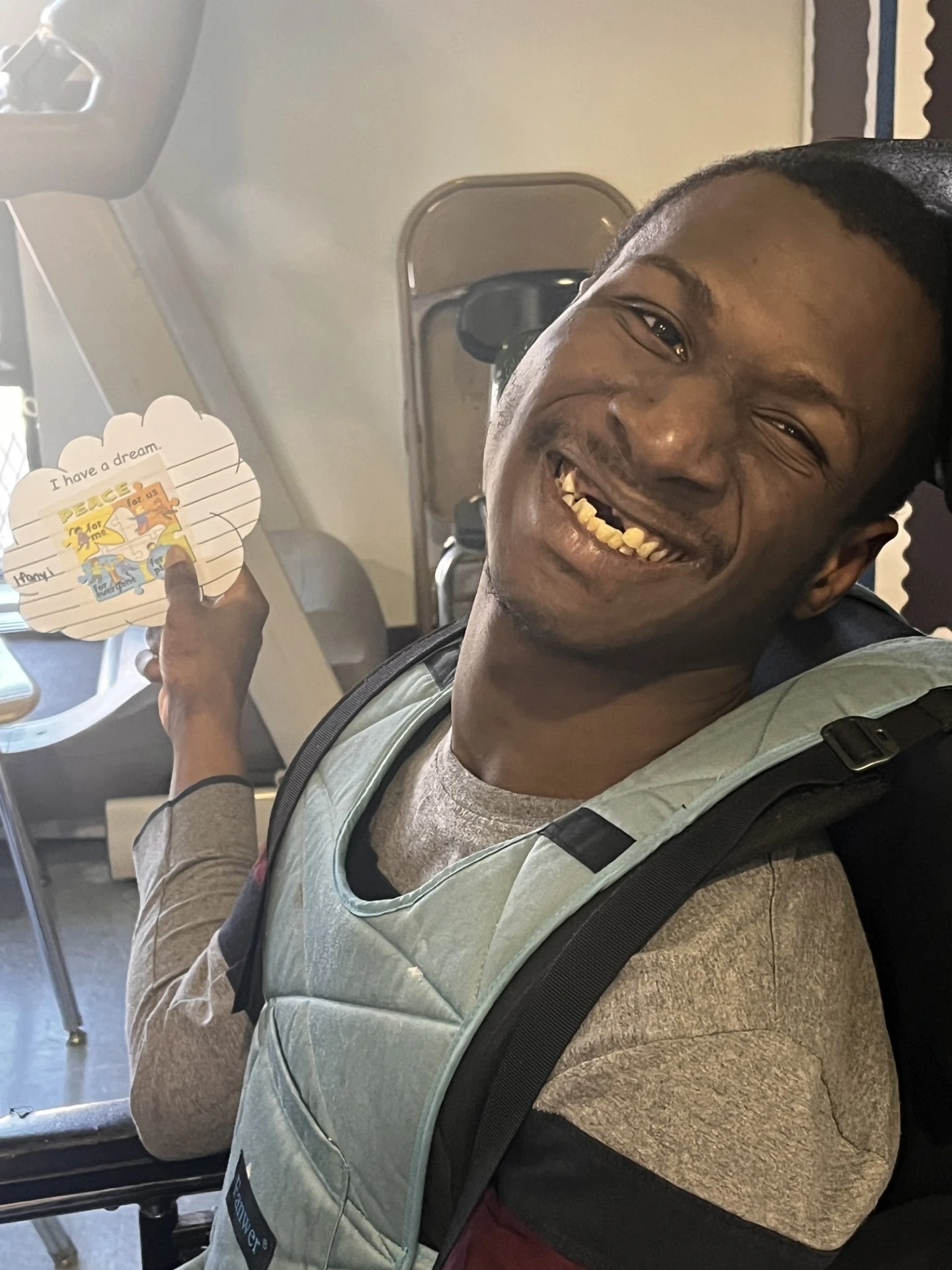Student in a manual wheelchair holding up a sign related to the class reading