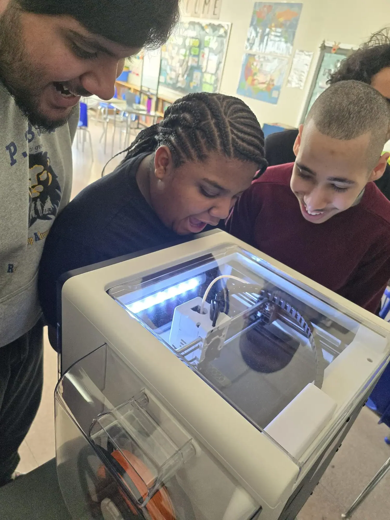 3 students watching a 3d printer work
