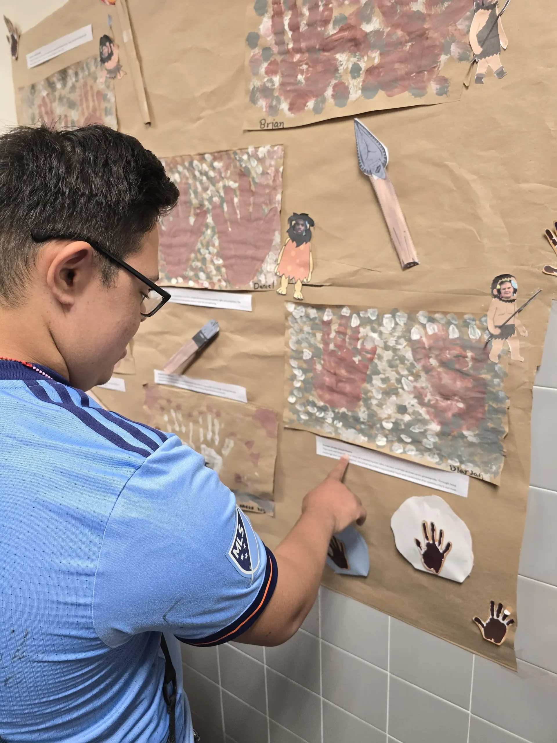 Student exploring an informational board about cavemen curriculum. student exploring an information board about cavemen