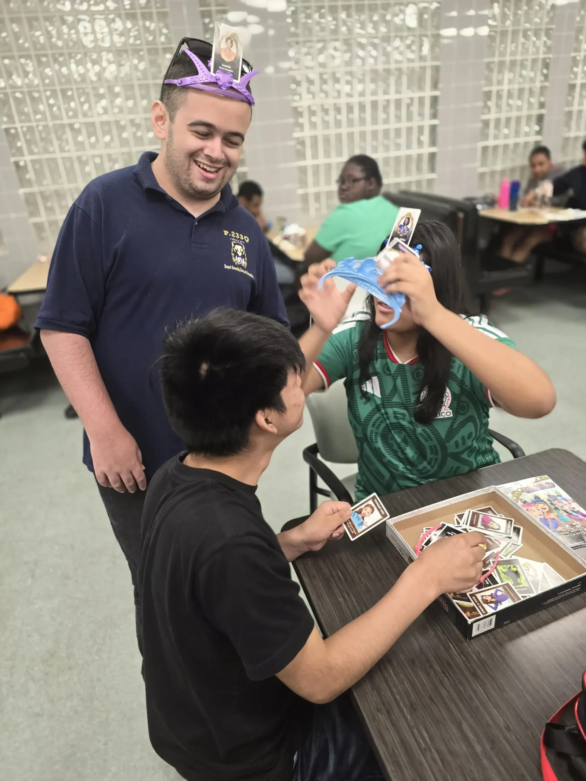 three students where plastic crowns playing a card game three students where plastic crowns playing a card game